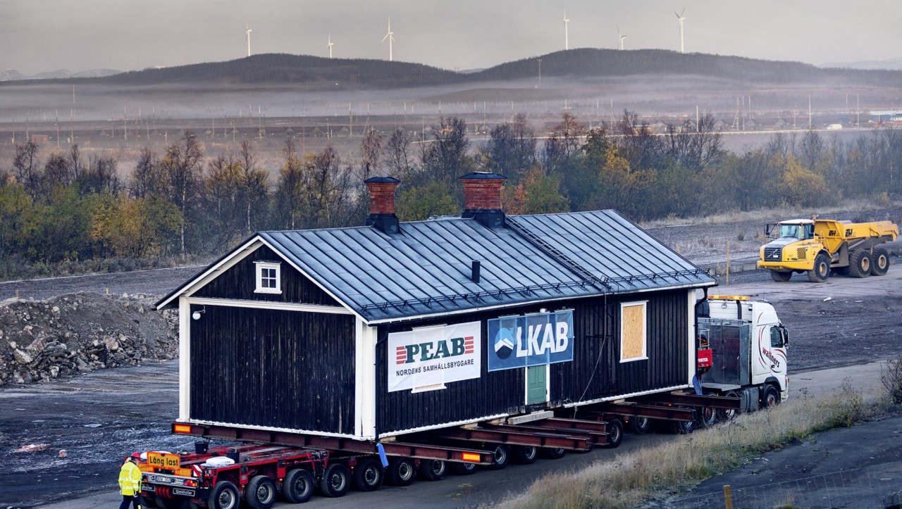 Zijaanzicht van het museum in Kiruna dat wordt verplaatst, met windmolens op de achtergrond